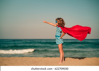 Ready to travel! Superhero child on the beach. Super hero kid having fun outdoor against sea and sky background. Girl power. Summer vacation concept - Powered by Shutterstock