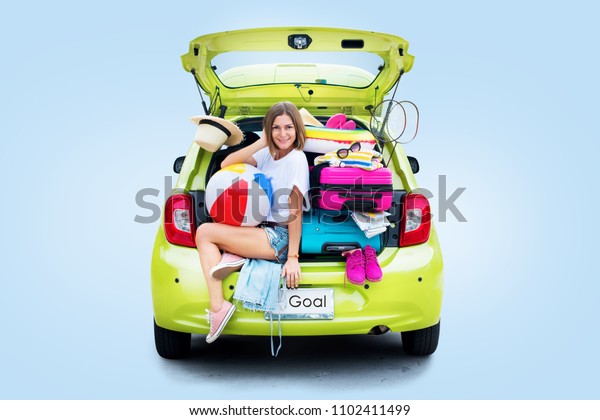 Ready to travel. Woman\
before Trip in Green Overloaded Car with Things. Bright Suitcases\
Luggage Accessories Clothes. Summer Concept Holiday Adventure\
Isolated on Blue