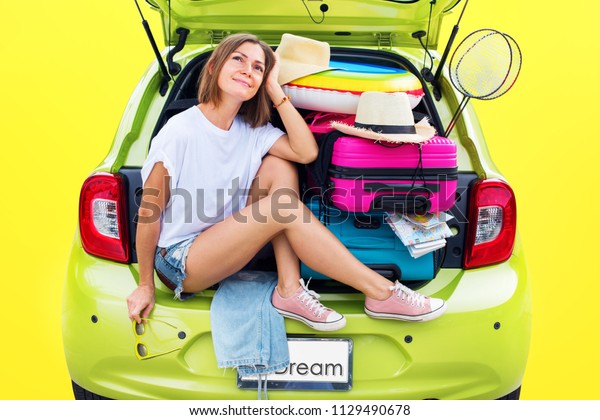 Ready to travel. Young Woman in Green Overloaded\
Car Luggage Carrier Stuff Things before Trip Bright Suitcases\
Luggage Full Accessories Clothes Ballon Summer Concept Holiday\
Adventure Isolated Yellow