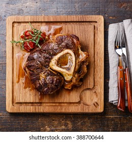 Ready-cooked Osso buco Veal shank on serving board on wooden background