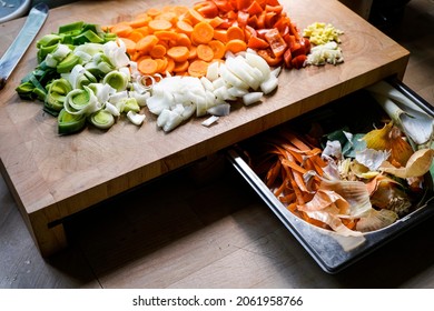 Ready-cut Raw Vegetables, Prepare For Cooking On A Wooden Board And Next To It In A Silver Bowl The Organic Compost.