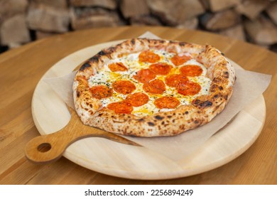 Ready-made Italian pizza on a wooden plate is ready to be served in the restaurant - Shutterstock ID 2256894249