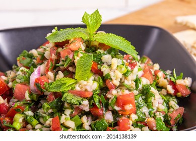 Ready-made tabbouleh salad in a bowl with mint leaves, close-up