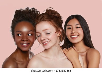 The real beauty exists in every corner of the world and is presented by women of all races. Beauty portrait of three smiling ladies with different skin colour on the pink backdrop.