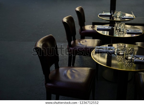 Real black wood table with red leather chair   at the\
bar or restaurant during night. knife and fork lie on white napkin.\
night scene. 