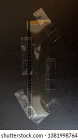 real blank 35mm filmstrip with cellotape or glue on dark wooden background