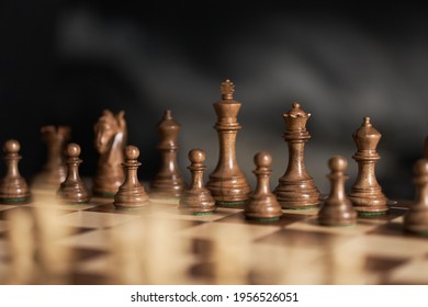 real chess pieces on a dark background made of quality boxwood wood. The beginning of a piece's game in its original position. Strategic chess game - Powered by Shutterstock