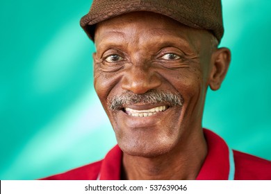 Real Cuban People And Feelings, Portrait Of Happy Senior African American Man Looking At Camera. Cheerful Old Latino Grandfather With Mustache And Hat From Havana, Cuba