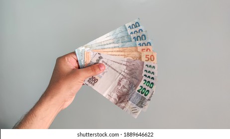 Real currency, money from Brazil. Brasil, Dinheiro, Reais, Hand. People holding in hand a brazilian banknotes.