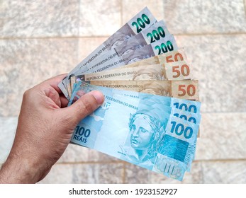 Real Currency, Money From Brazil. Brasil, Dinheiro, Reais, Hand. People Holding In Hand A Brazilian Banknotes.