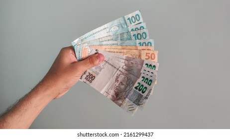 Real Currency, Money From Brazil. Brasil, Dinheiro, Reais, Hand. People Holding In Hand A Brazilian Banknotes.