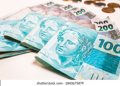 Real currency, money from Brazil. Dinheiro, Brasil, Reais, Real Brasileiro. Brazilian Banknotes of 100 reais and 200 reais and coins on a white surface.