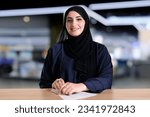 Real Emirati Arab woman indoors ideal for corporate banking or office counter table. Arabic Emarat national on Hijab Abaya