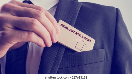 Real Estate Agent in Black Suit Putting Small Wooden Piece with Real Estate Agent Text and Graphic to Front Pocket. - Shutterstock ID 227613181