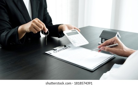 Real estate agent broker hand over the house key to the new owner after completing the signing according to agreement renting a house and buy house insurance Home insurance concept. - Shutterstock ID 1818574391