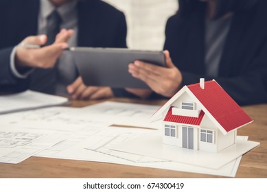 Real estate agent with client or architect team discussing project on tablet computer
