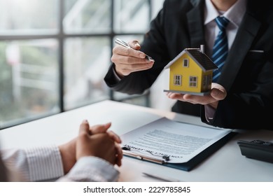 Real estate agent and customer make contract to buy and sell house and land approval of a contract to buy or sell a home offers mortgage loans and home insurance concept. - Shutterstock ID 2229785845