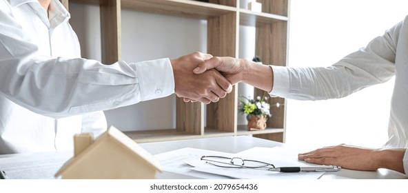 Real estate agent and customers shaking hands together celebrating finished contract after signing about home insurance and investment loan, handshake and successful deal.