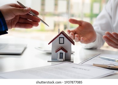 The real estate agent is explaining the house style to the clients who come to contact to see the house design and the purchase agreement. Within a modern office