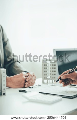 A real estate agent is explaining the layout of a house to a client who is about to buy a new apartment along with insurance interest rates on the title. Close-up photo