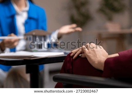 Real estate agent gesticulates while explaining a house model to a client