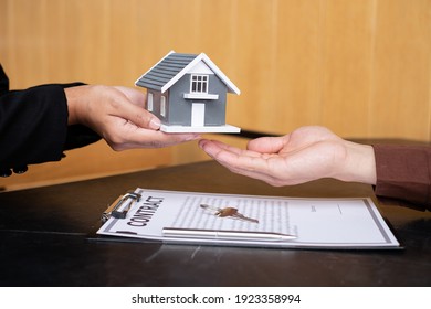 A real estate agent gives the house to a new owner's client after completing the signing of the lease and formally completing home insurance. Rental and insurance concepts.