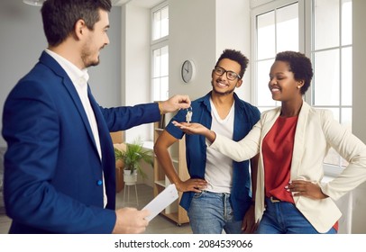 Real Estate Agent Gives House Keys To Young Married Black Couple. Happy Ethnic Boyfriend And Girlfriend Or Husband And Wife Meeting With Realtor To Make A Deal And Take Keys To Their New Apartment