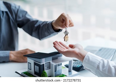 Real estate agent giving house key to the client after signing the real estate contract. Home and real estate trading concept. - Powered by Shutterstock