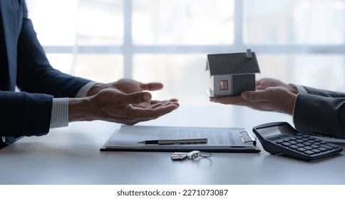 Real estate agent giving house key to the client after signing the real estate contract. Home and real estate trading concept. - Powered by Shutterstock