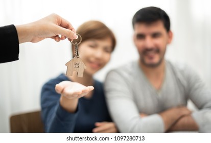 Real Estate Agent giving key of new house to Young couple. Happy man and woman smiling. - Shutterstock ID 1097280713