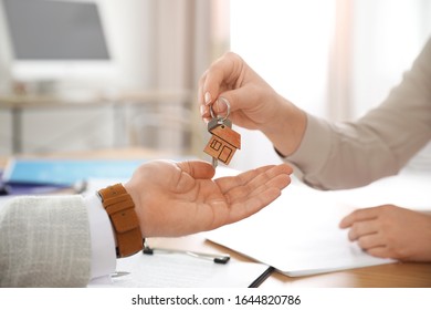 Real estate agent giving key with trinket to client in office, closeup - Shutterstock ID 1644820786