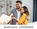 Real estate agent giving keys to young indian buyers, happy woman taking key of future new apartment, spouses buying new house