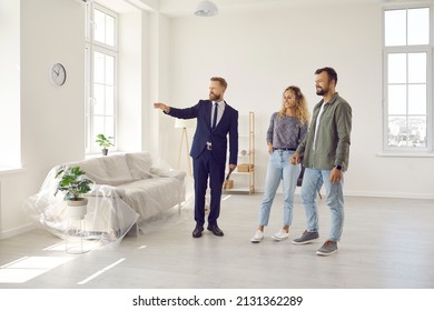 Real estate agent giving potential buyers or future tenants tour about big new house. Boyfriend and girlfriend or husband and wife who plan property investment looking at lovely modern spacious home - Shutterstock ID 2131362289