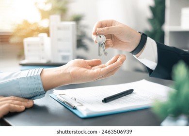 Real estate agent handed over the key to new home, marking a successful investment in business of property, whether it be a house or an apartment. Real estate agent giving house key to customers. - Powered by Shutterstock