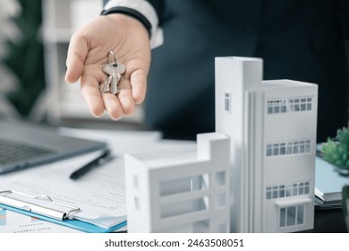 Real estate agent handed over the key to new home, marking a successful investment in business of property, whether it be a house or an apartment. Real estate agent giving house key to customers. - Powered by Shutterstock