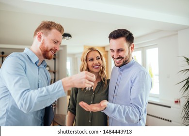 Real estate agent handing over the key to the happy couple