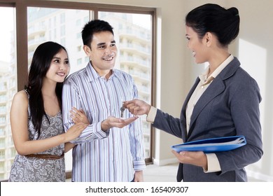 Real Estate Agent Handing Over Keys Of New House To Young Couple