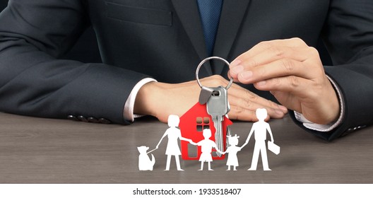 Real Estate Agent Handing Over House Keys In Hand, Showing Protecting Paper Chain Family