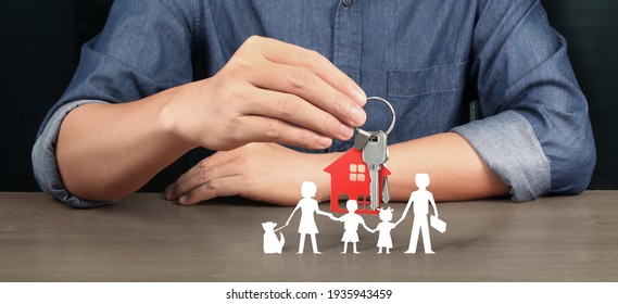 Real Estate Agent Handing Over House Keys In Hand, Showing Protecting Paper Chain Family