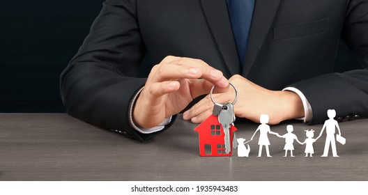 Real Estate Agent Handing Over House Keys In Hand, Showing Protecting Paper Chain Family