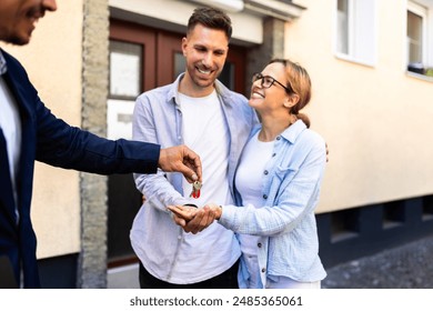 Real estate agent handing over keys to a young couple for their new home. Property ownership transfer complete. - Powered by Shutterstock