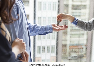 Real Estate Agent Handing Over A Key To A Couple