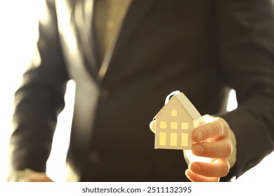 Real estate agent holding toy house - Powered by Shutterstock