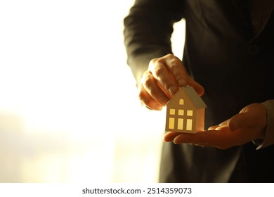 Real estate agent holding toy house - Powered by Shutterstock