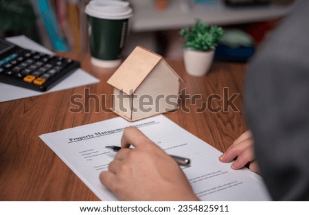 real estate agent with house. Business person holding pen sign a contract approved on mortgage loan contract agreement document house plan on the table.