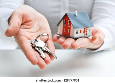 Real estate agent with house model and keys - Shutterstock ID 129797951