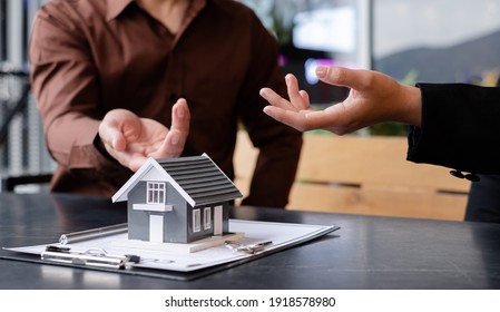 A real estate agent with a House model is talking to clients about buying home insurance. Home insurance concept.