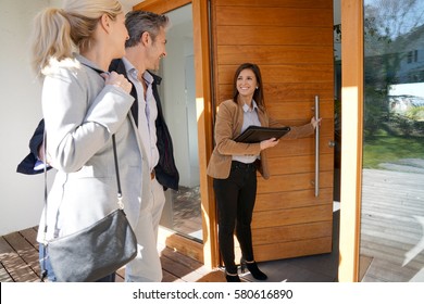 Real Estate Agent Inviting Couple To Enter House For Visit                     