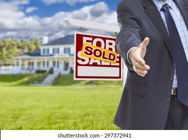 Real Estate Agent Reaches For Handshake With Sold Sign And New House Behind.