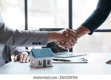 Real estate agent shakes hands with a client to sign a home purchase contract congratulating the client on the purchase. - Shutterstock ID 2261325765